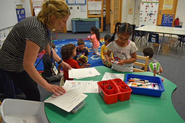 A teacher helps a student practice writing her name.